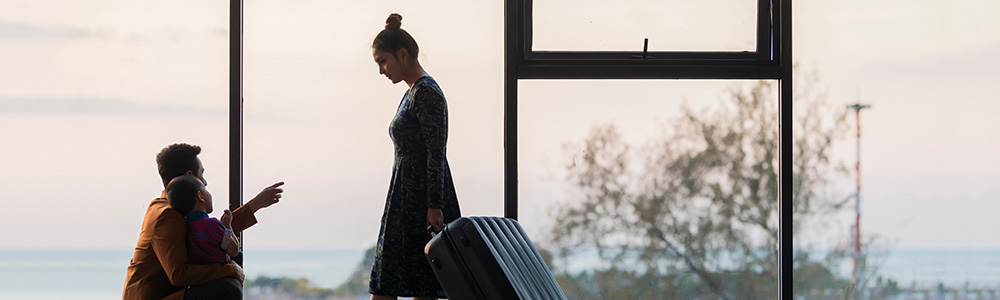 Dad and son looking up at mother walking with suitcase