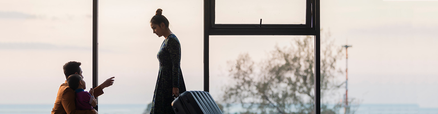 Dad and son looking up at mother walking with suitcase